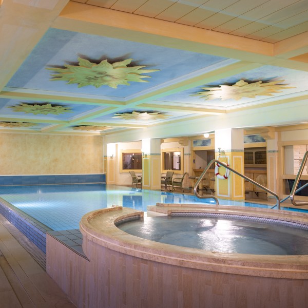 Eleganter Innenpool mit Whirlpool und kunstvoller Decke im Wellnessbereich eines Luxushotels